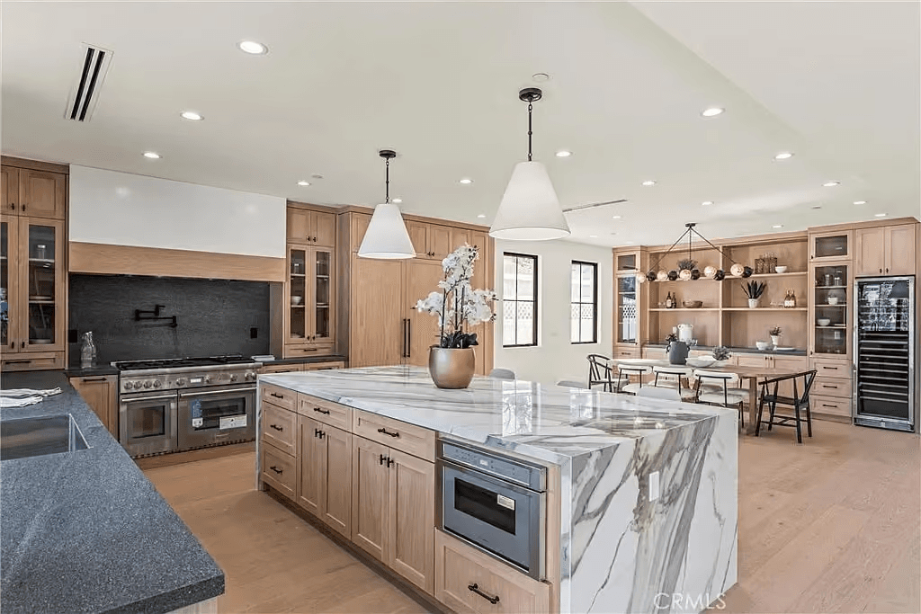 Bright custom kitchen with warm wood cabinetry and a marble island